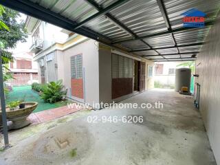 Covered outdoor area with adjacent house and small garden