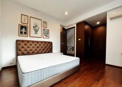 Spacious bedroom with a bed, wall art, wooden flooring and built-in closet