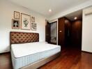 Spacious bedroom with a bed, wall art, wooden flooring and built-in closet