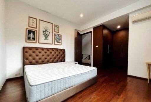 Spacious bedroom with a bed, wall art, wooden flooring and built-in closet