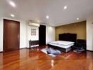 Spacious bedroom with wooden flooring, ceiling lights, and a double bed