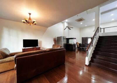 Spacious living room with leather sofas, a TV, and a staircase leading to the upper floor