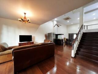 Spacious living room with leather sofas, a TV, and a staircase leading to the upper floor