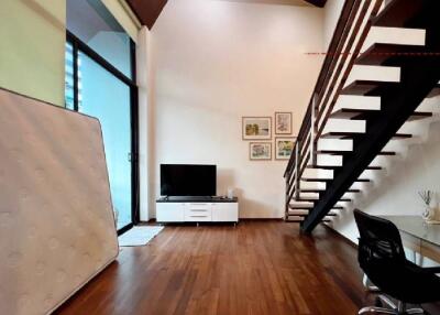 Living room with wooden floor, television, and staircase