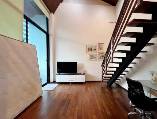 Living room with wooden floor, television, and staircase