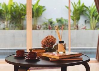 Coffee table with books, candles, and cups with view of garden