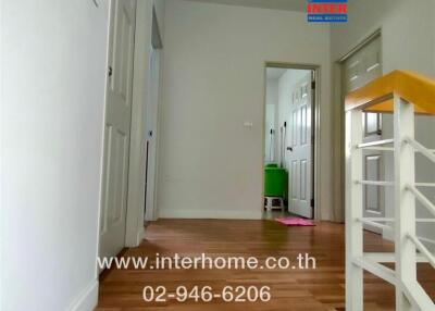 Interior hallway view leading to multiple rooms with wooden flooring