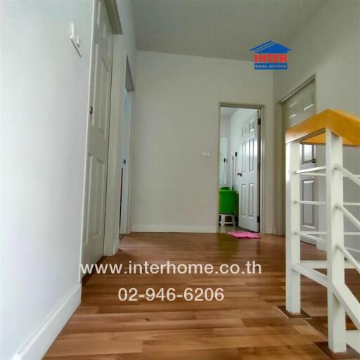 Interior hallway view leading to multiple rooms with wooden flooring