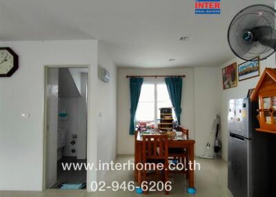 Kitchen and dining area with dining table, refrigerator, wall clock, and window with curtains.