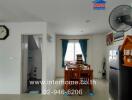 Kitchen and dining area with dining table, refrigerator, wall clock, and window with curtains.