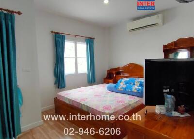 Bedroom with bed, window, curtains, wooden furniture, wall-mounted air conditioner, and a TV