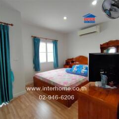 Bedroom with bed, window, curtains, wooden furniture, wall-mounted air conditioner, and a TV