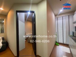 Photo of an apartment interior with visible restroom door, living area, and partial kitchen.