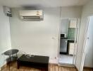 Living room with air conditioning unit, coffee table, and view into the kitchen