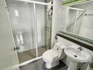 Modern bathroom with glass shower enclosure, toilet, and sink