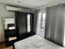 A modern bedroom with a large window, wardrobe, vanity table, and double bed.