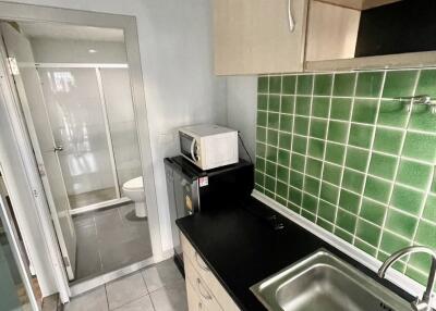 Small kitchen area with green tiled backsplash and sink