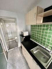 Small kitchen area with green tiled backsplash and sink