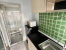 Small kitchen area with green tiled backsplash and sink