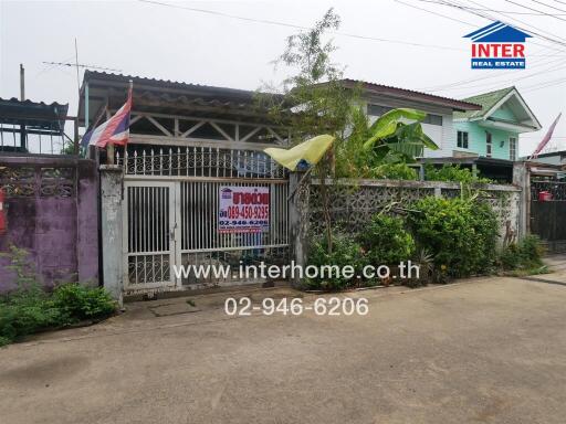 Front view of a house with a fenced gate and surrounding greenery