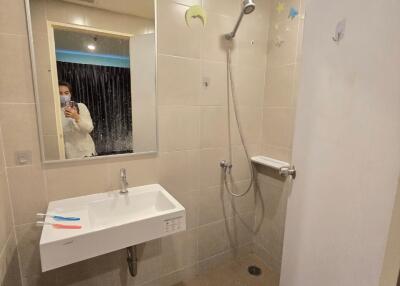 A modern bathroom with a wall-mounted sink and a walk-in shower.