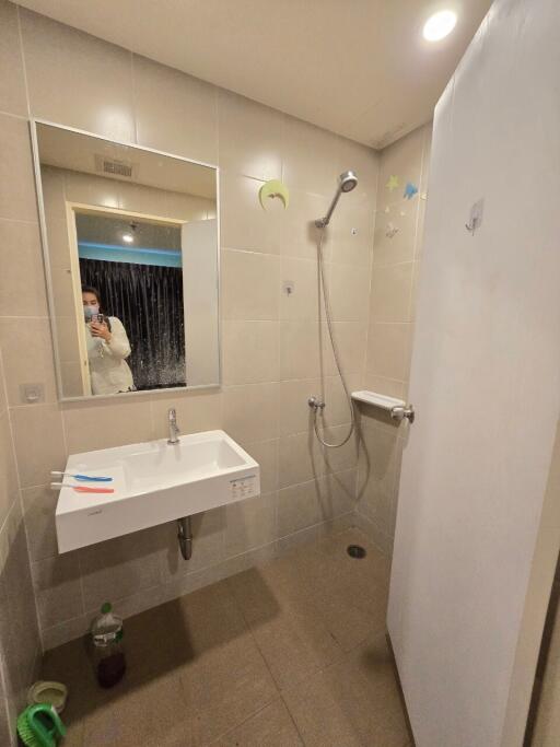 A modern bathroom with a wall-mounted sink and a walk-in shower.