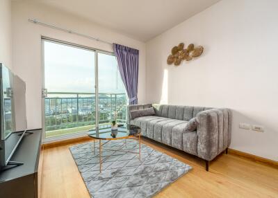 Modern living room with a gray couch, TV, and a balcony view