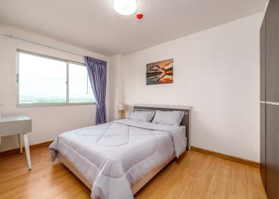 Modern, well-lit bedroom with a bed, a wardrobe, and a window with a view