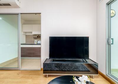 Living room with a TV and view into the kitchen