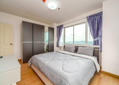 Spacious bedroom with a large bed, wardrobe, and window view