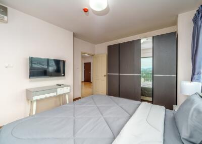 Modern bedroom with a double bed, wall-mounted TV, and a large wardrobe