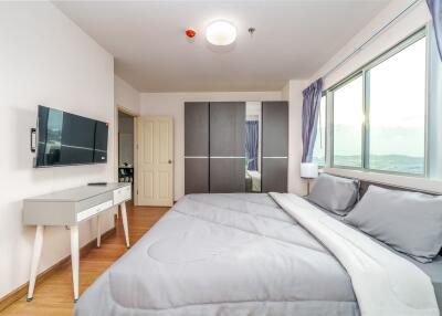 Modern bedroom with large bed, wall-mounted TV, and natural light