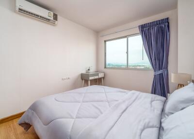 Bright bedroom with a large window, curtains, air conditioning unit, and modern decor