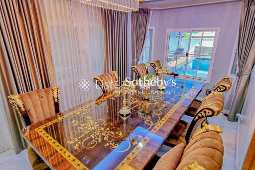 Luxurious dining room with ornate chairs and a glass-top table, featuring pool view