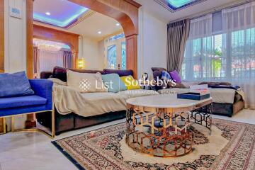 A well-furnished living room with sofas, coffee table, and large windows.