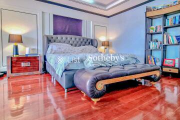 Luxurious master bedroom with hardwood flooring and cozy seating area