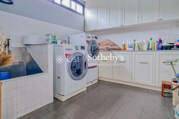 Laundry room with washing machine, dryer, sink, and storage cabinets