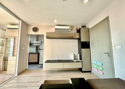 Modern living room with wooden flooring, wall-mounted air conditioner, and built-in shelves