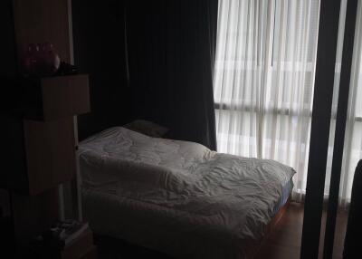 Dimly lit bedroom with a bed and curtains