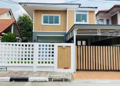 Front exterior view of a modern two-story house with a fenced yard