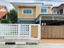 Front exterior view of a modern two-story house with a fenced yard