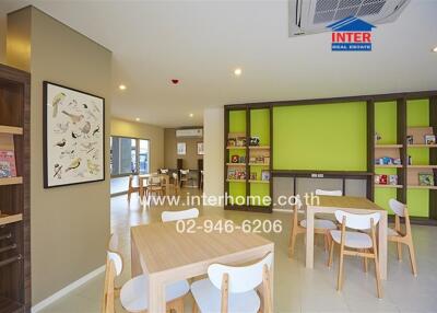 Modern living area with tables and chairs, vibrant green wall, and bookshelves