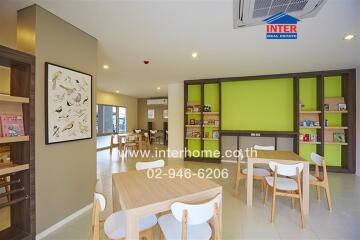 Modern living area with tables and chairs, vibrant green wall, and bookshelves