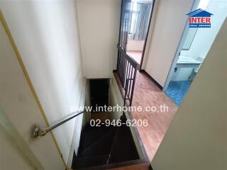 Staircase leading to lower level with view of adjacent bathroom and living space