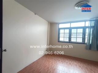 Dimly lit bedroom with window and wood flooring