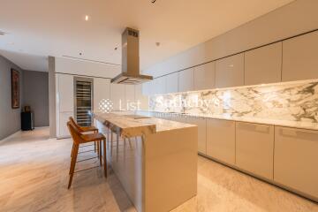 Modern kitchen with island, barstools, marble countertops, and built-in appliances