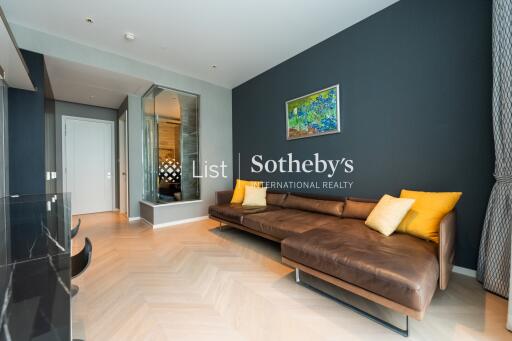 Modern living room with a brown leather sectional sofa, wooden flooring, and a large mirror on the wall