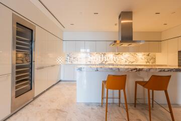 Modern kitchen with marble countertops and orange bar stools