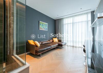 Modern living room with a large window, hardwood floor, and a comfortable brown leather sofa