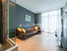 Modern living room with a large window, hardwood floor, and a comfortable brown leather sofa